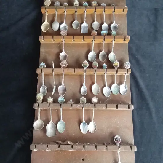 VINTAGE SOUVENIR TEASPOONS ON A WOODEN WALL DISPLAY RACK