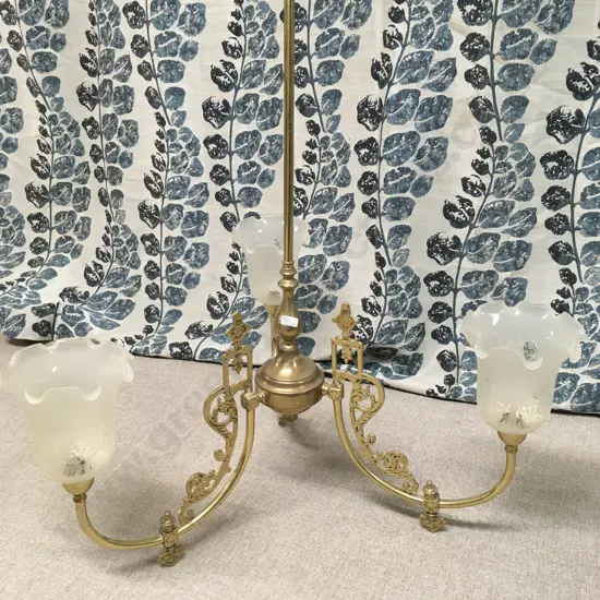 ANTIQUE THREE-ARM BRASS CHANDELIER WITH FROSTED GLASS SHADES.